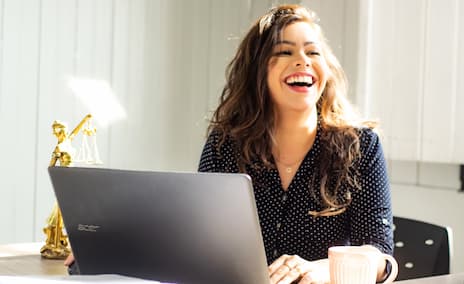 Photo d'une collaboratrice souriante derrière son ordinateur dans son entreprise
